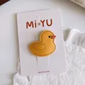 Detail of yellow leather cartoon duck hair clip showing fine stitching on white lace - Little Duck