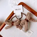 Close-up of brown knitted bow hair ties with floral accents on white paper card - Swallowtail Bow Hair Tie
