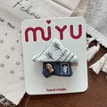 Detail of handmade fabric hair clip in house shape with fish charm on display card - House