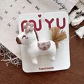 Detail of a handmade 3D pony hair clip with embroidery on a wooden table background - Pony