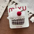 Close-up of handmade cupcake hair clip with white fleece, red cherry, and lace details - Cake