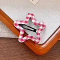 Close-up of star-shaped red and white gingham fabric hair clip on a wooden tray - Star Style