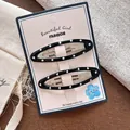 Close-up of 2 black oval BB hair clips with white polka dots on pink card packaging - Black