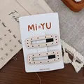 Détail de barrettes en similicuir à pois rouges avec coutures fines sur fond de bois - Beige Carré