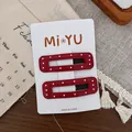 Détail de barrettes à pois rouges sur une carte sur fond en bois avec un décor chaleureux - Bordeaux Rectangle