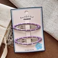 Dettaglio di due fermagli per capelli ovali viola a pois su una scheda decorativa rosa - Viola