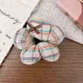Close-up of a flower-shaped plaid scrunchie with a small brown bow on a rustic background - Coffee Plaid