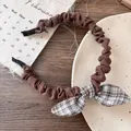Détail d'un serre-tête en tissu plissé marron avec un nœud élégant à carreaux bicolores - Serre-tête à Carreaux avec Nœud