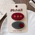 Détail de barrettes en velours côtelé gris et rouge avec paillettes et boutons - Groupe Elliptique À 4 Éléments