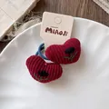 Détail de chouchous cœur en velours côtelé rouge avec broderie sur assiette blanche - Élastique à Cheveux Coeur