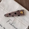 Détail macro d'une barrette en peluche marron à pois noirs et bouton doré gravé 'LUCK' - Style Triangle (4-Petit Triangle)