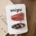 Close-up of pink velvet bow clip and vintage plaid button hairpin on display card - Velvet Button Style / Oval Plaid