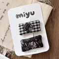Détail de barrettes en tissu à fleurs et carreaux sur carte sur une table en bois - Style Vintage Noir et Blanc / Carreaux Noirs