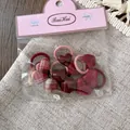 Detail of 10-piece girls' hair ties set featuring plaid hearts and pink elastic bands - Red Heart
