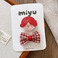Detail von roten Cartoon-Mädchen- und karierten Schleifen-Haarspangen auf Displaykarte - Rotes Mädchen