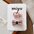 Details von rosa Apfel-Haarclip und Karo-Schleife auf einem Marken-Karton aus weißem Papier - Rosa Apfel