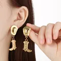 Close-up of golden stainless steel cowboy hat and boot dangle earrings on model's ear - Vintage Embossed Hat Boot Style (KE121857-SXSJ)