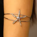 Detail view of a silver textured starfish arm cuff bracelet worn on an upper arm - Starfish / White K Gold