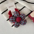 Detalle de un coletero de terciopelo rojo con una flor de cuadros pata de gallo azul - Coletero de Flor