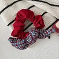 Vista macro del coletero de tela roja con un lazo con estampado de pata de gallo - Scrunchie con Lazo