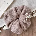 Macro detail of plush teddy fleece scrunchie with button and bow decoration - Brown
