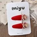 Detail of red velvet hair clips with golden bows and iridescent heart rhinestones - Heart