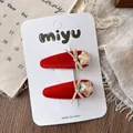 Detailed view of red velvet hair clips with gold bows and iridescent star accents - Star