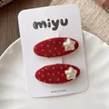 Close-up of red polka dot hair clips with golden stars on a decorative ceramic plate - 4-Star Set