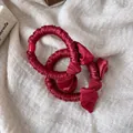 Nahaufnahme weinroter Satin-Haargummis mit eleganter Schleife und Faltenstruktur - Schleifen-Dekorationsstil / Burgunderrot
