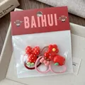 Detail of red cartoon hair ties for girls including strawberry and bow resin charms - Polka Dot Bow Style
