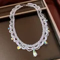 Close-up of iridescent glass beaded lace necklace featuring teardrop crystal pendants detail - Necklace-White