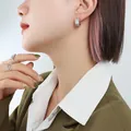 Silver C-shaped wide hoop earrings with zircon stars on fashion model close-up - Steel