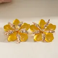 Exquisite close-up detail of yellow enamel pleated flower earrings with a golden metallic finish - Steel Post Studs / Yellow