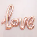Detail of rose gold Love letter foil balloon showing metallic sheen and texture on a beige background - Champagne Gold
