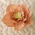 Makroaufnahme einer Pfirsich-Krepppapierblume mit gelben Staubblättern auf Steppstoff - Klein / Lotusrosa