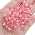 Pink transparent acrylic letter beads for DIY jewelry making held in a hand - Alphabet Beads / 6x6mm Hole 4mm 100 Pieces/Pack / Transparent Pink with White Letters