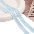 Vista macro de cinta de encaje con pompones azul claro y malla tejida para costura DIY - Azul claro
