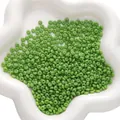 Platte grasgroene glazen kralen voor DIY sieraden maken in witte keramische kom - Groen
