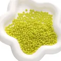 Neon groene glazen kralen voor DIY sieraden in een witte keramische bloemschaal - Geel