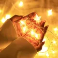 Close-up of star-shaped LED fairy lights emitting warm yellow glow in hands - Star Lamp / Warm Tone