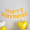 Macro view of Happy Birthday felt banner with yellow hearts and matching party balloons - Yellow