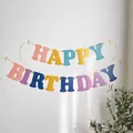 Dettaglio dello striscione Happy Birthday con lettere colorate su una parete bianca - Colori Misti Macaron