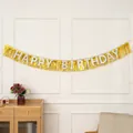Detalle del cartel Happy Birthday con flecos dorados en una pared blanca - Dorado