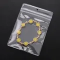 Gelbes Katzenaugen-Perlenarmband mit Golddetails im PVC-Beutel mit Aufhängeloch - Großer Stil