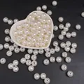 Perle tonde in ABS bianco crema con fori centrali in un piatto a cuore per gioielli fai da te - Perline rotonde / 10mm (100 Pezzi/Confezione) / Beige