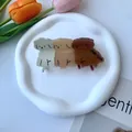 Dettaglio di tre mollette per capelli a forma di cucciolo in resina su vassoio in ceramica - Tre Cani Marrone