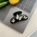 Black hair claw clip featuring white butterflies and green crystals on a laptop - Black Glass Diamond Butterfly