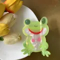 Detail einer grünen Frosch-Haarklammer aus schillerndem Acetat auf einem weißen Teller - Süßer Frosch