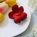 Macro detail of a red five-petal flower hair claw clip displayed on a white tray - Red Blue Patchwork
