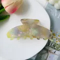 Macro shot of large colorful marbled acetate hair claw clip with pearlescent shell texture - Yellow Dazzling